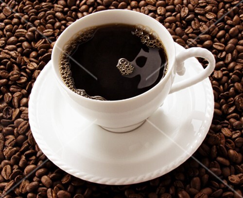 Cup of Black Coffee Resting on Coffee Beans