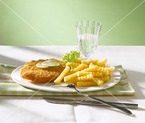 Wiener Schnitzel with lime slices, chips & glass of water