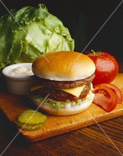Double Cheeseburger und Zutaten auf einem Holzbrett