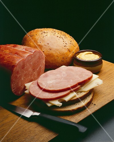 Slices of Ham and Swiss Cheese on Rye Bread; On Cutting Board