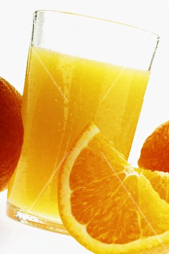 Orangensaft im Glas zwischen Orangen