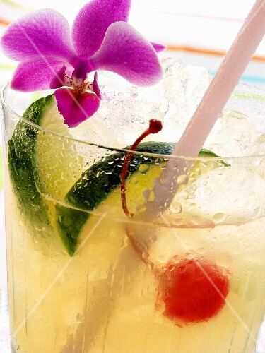 Drink with lime, ice, cocktail cherry and orchid (2)
