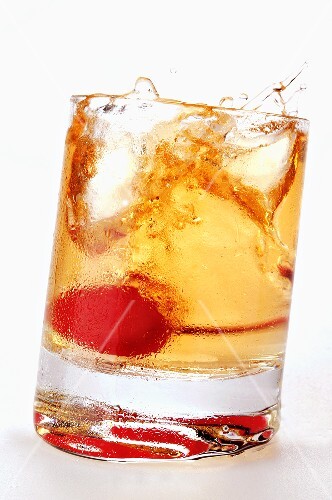 Ginger Ale with cocktail cherry splashing out of glass