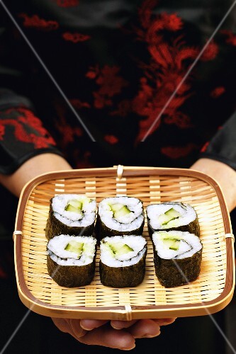 Asiatin hält Maki-Sushi auf Korbtablett