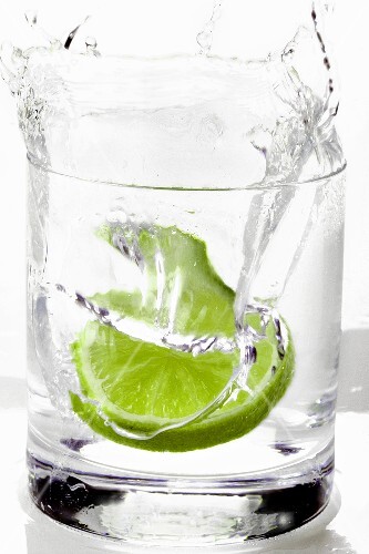 Limettenscheibe fällt in einen Drink