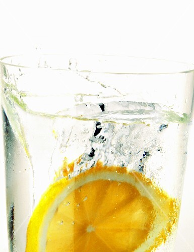 Zitrone fällt in Wasserglas (Close up)