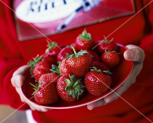 Boy holding plate of strawberries