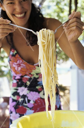 Junge Frau nimmt sich Spaghetti aus einem Plastikseiher