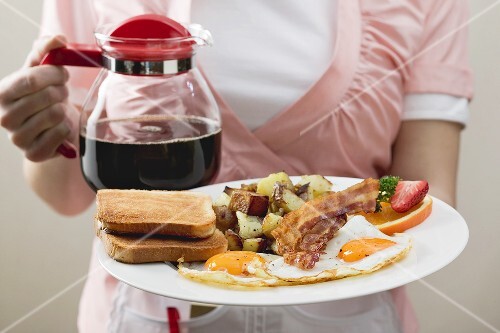 Kellnerin serviert Kaffee und Spiegelei, Bacon, Hash Browns