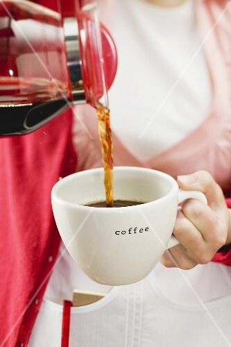 Kellnerin giesst Kaffee in Tasse