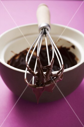 Remains of chocolate sauce in pot and on whisk