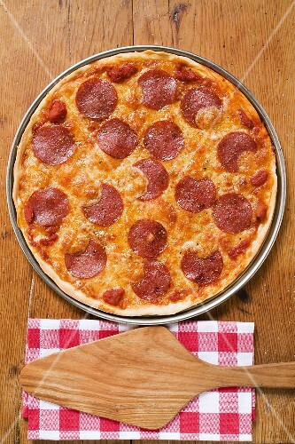 Whole pepperoni pizza, server on napkin beside it