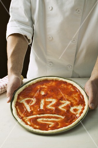 Pizza base spread with tomato sauce, with the word Pizza