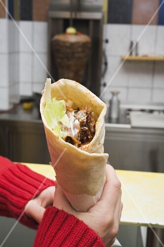 Hands holding döner wrap in snack bar