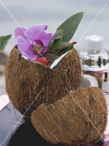 Opened coconut with orchid, sea in background