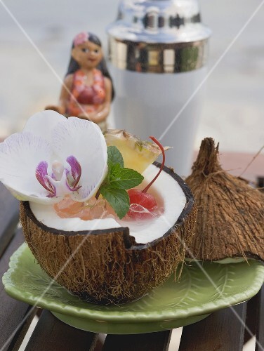 Coconut drink with ice cubes, cocktail cherry and orchid