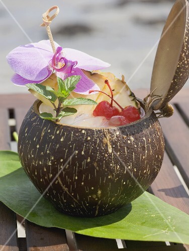 Coconut drink with pineapple, cocktail cherry and orchid