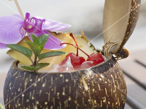Coconut drink with pineapple, cocktail cherry and orchid