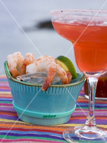 Red cocktail in glass, shrimps with dip beside it