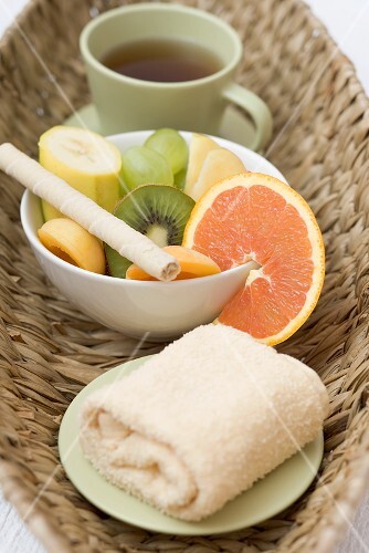 Cup of tea, fresh fruit and towel in basket