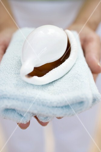Woman holding shell on towel