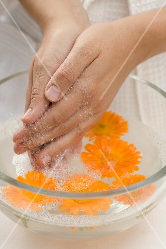 Woman washing her hands in soapy water with marigolds
