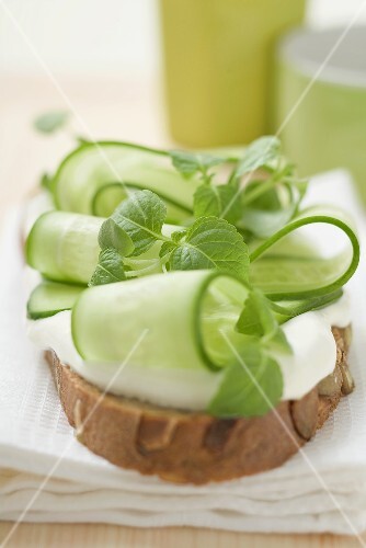 Belegtes Brot mit Joghurt, Gurkenscheiben und Kräutern
