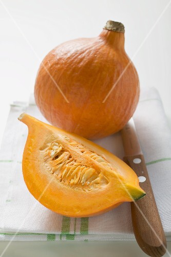 Hokkaido pumpkins (whole and quarter) on tea towel, knife