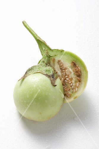 Green mini-aubergine, halved, with drops of water