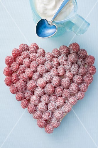 Raspberry tart with icing sugar, whipped cream in small jug