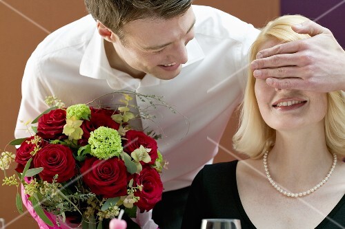 Man surprising woman with a bouquet of flowers