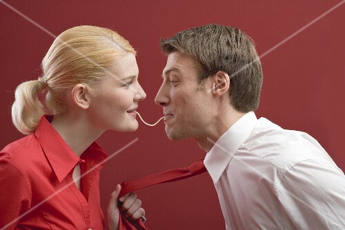 Couple eating a strand of spaghetti from both ends