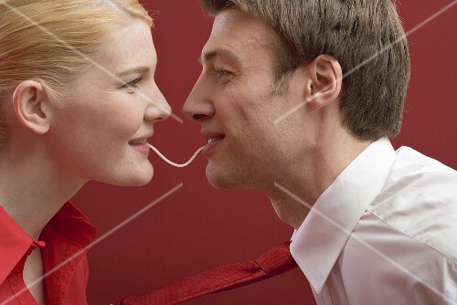 Couple eating a strand of spaghetti from both ends