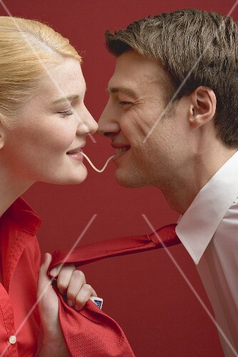 Couple eating a strand of spaghetti from both ends