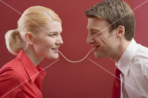 Couple eating a strand of spaghetti from both ends