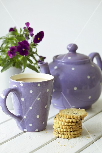 Teapot, mug of tea, fruit shortcakes and pansies