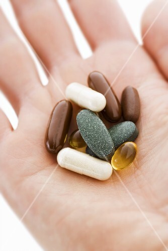 Verschiedene Tabletten und Kapseln auf Hand