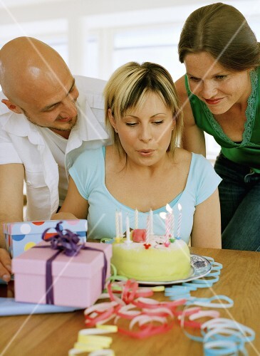 Woman blowing out candles on her birthday cake