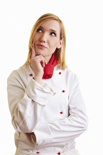 Nachdenkliche blonde Köchin in Arbeitskleidung