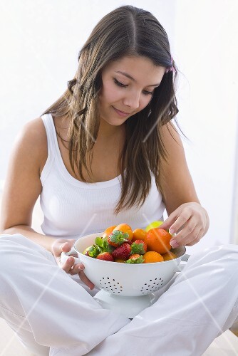 Girl looking at a kitchen sieve with fresh fruit