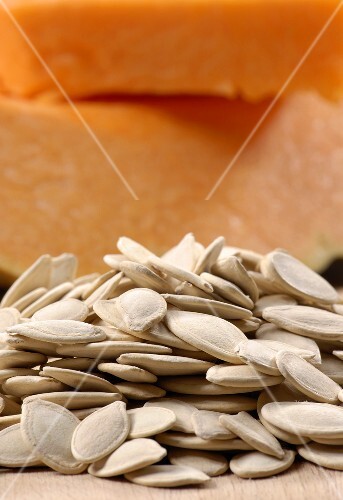 Dried pumpkin seeds with pumpkin in the background