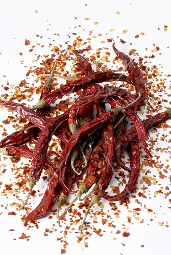 Chilli peppers with crushed chilli on a white background