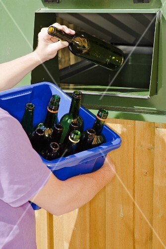 Person wirft Flasche in Müllcontainer
