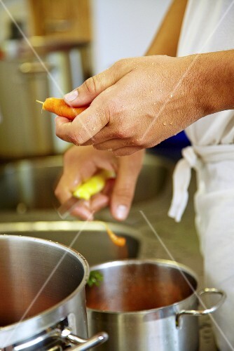 Koch in Grossküche schält Karotten