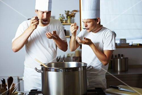Zwei Köche probieren gemeinsam Suppe aus Kochtopf
