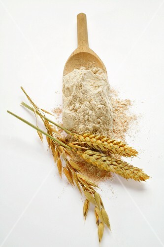 Wholemeal flour on wooden scoop; cereal ears
