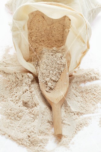 Wholemeal flour in sack with wooden scoop