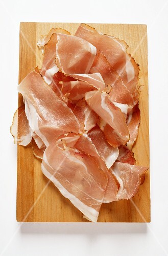 Slices of raw ham on chopping board