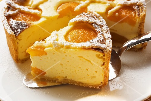 Piece of apricot cheesecake in front of cut cake