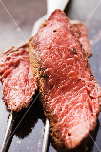 Two slices of beef steak on meat fork